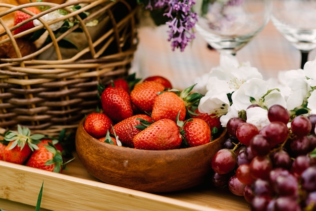 Canasta de picnic con fresas, uvas y vasos.