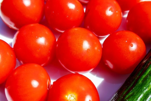 una canasta de tomates con un pepino verde encima.