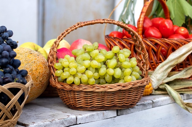 Canasta con uvas y canasta con tomates en una mesa de madera para mostrar la cosecha