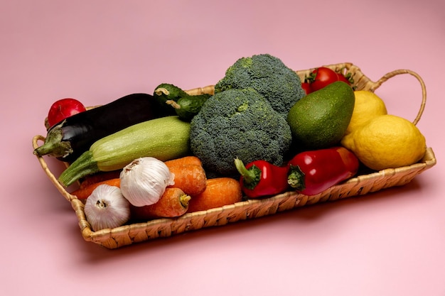 Una canasta de verduras con un pimiento rojo encima