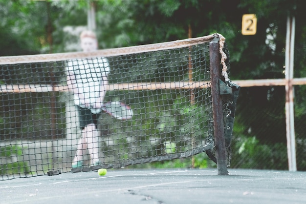 Cancha de tenis con pelota y red en un día de verano bajo el sol