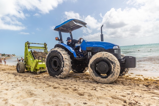 Cancun mexiko 19. märz 2022 traktor zieht algensammelmaschinen am strand in einem sommerresort, um die strände sauber zu halten