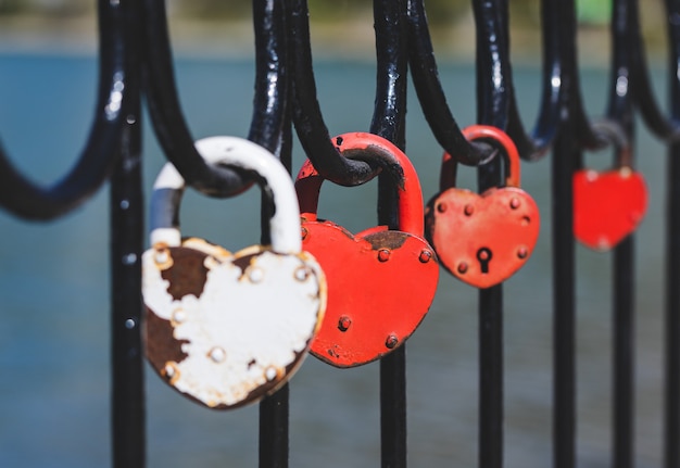 Un candado de amor rojo unido a la barandilla del puente.