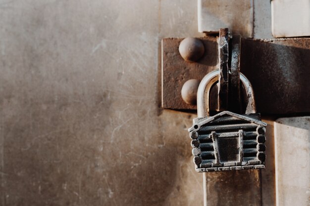 Foto el candado en forma de choza cuelga de las bisagras de la puerta cerrada. puertas de metal.