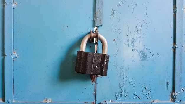 Un candado negro en una puerta de garaje de metal azul. De cerca.