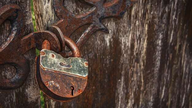 Foto un candado oxidado cuelga de una valla de madera.