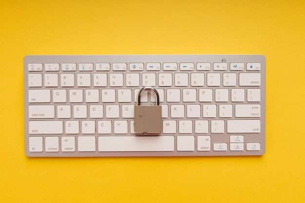 Candado en el teclado de la computadora sobre un fondo amarillo Concepto de seguridad de red y datos