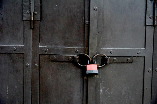 candado en una vieja puerta de metal negro forjado con rayas y remaches primer plano de fondo vintage pasaje cerrado y concepto de protección