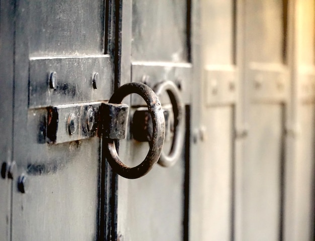 candado en una vieja puerta de metal negro forjado con rayas y remaches primer plano de fondo vintage pasaje cerrado y concepto de protección