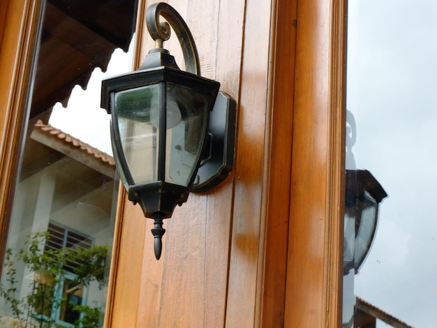 Candelabro de metal preto vintage. Pendurado na porta de madeira de teca de uma casa javanesa. Lampu Gantung.