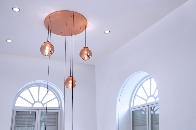 candelabro de vidro de ouro rosa redondo de teto moderno com janelas de madeira em arco dentro da sala de estar branca