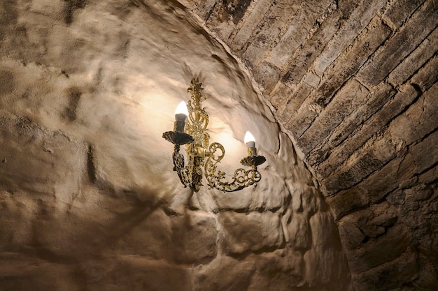 Candelabro de oro con dos velas en el antiguo muro de piedra del castillo. Rusia