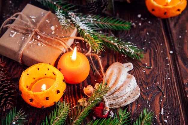 Candelabros de mandarinas con ramas de abeto nevado, juguetes y regalos en mesa de madera. Fondo de Navidad y año nuevo.