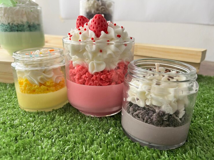 Candelas perfumadas hechas a mano en frascos sobre superficie de hierba