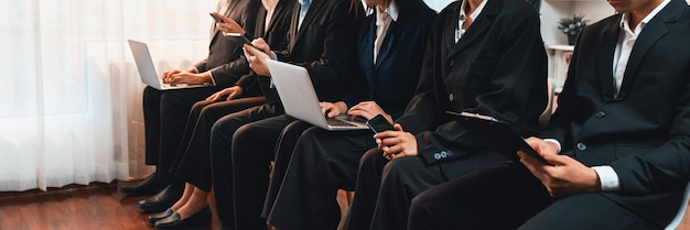 Candidato asiático a um emprego com roupas formais idênticas sentado na sala de espera para uma entrevista de emprego Trabalhador de escritório ou pessoas de negócios trabalhando em uma sala apertada juntos usando laptop e telefone