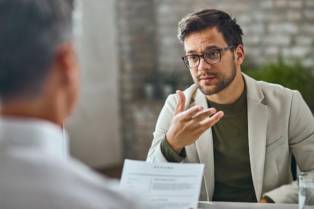 Candidato masculino joven que solicita trabajo y habla con un gerente en la oficina