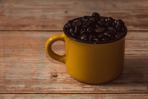 Caneca amarela cheia de grãos de café na superfície de madeira vintage Copiar espaço Foco seletivo