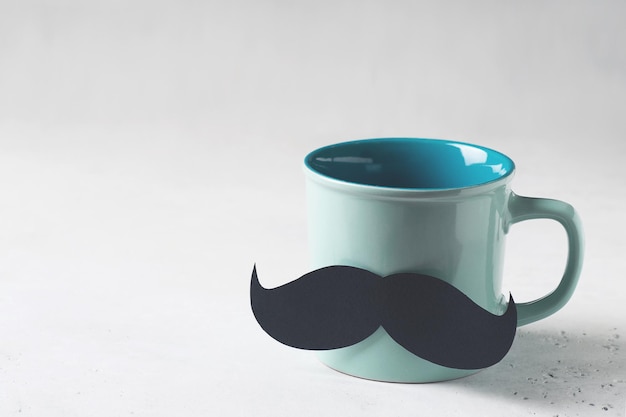 Caneca azul com bigode fecha o conceito de dia dos pais em fundo branco