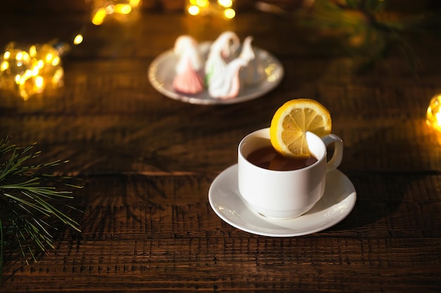 Caneca branca de chá com limão e marshmallows coloridos em um fundo de madeira