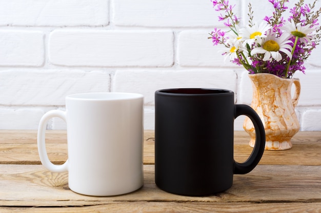 Foto caneca branca e preta com camomila e flores roxas no jarro de ouro