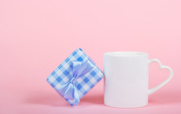 Caneca branca em fundo rosa e caixa de presente