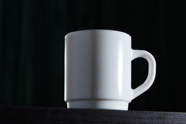 Caneca branca para chá e café em um fundo escuro fechado