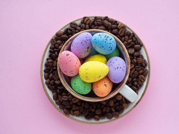 Caneca cheia de ovos coloridos no prato com grãos de café no fundo com espaço para cópia
