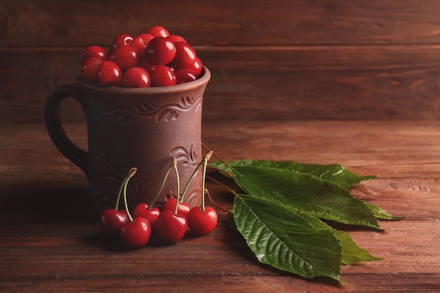 Caneca com cerejas em fundo de madeira