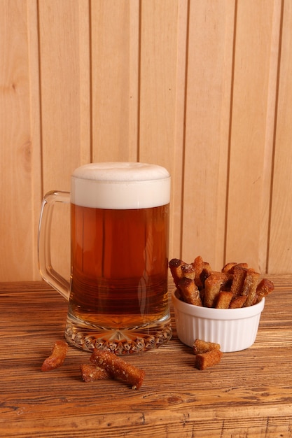 Caneca com cerveja light e biscoitos salgados em uma mesa de madeira