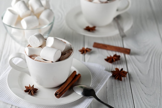 Caneca com chocolate quente e marshmallows na mesa de madeira