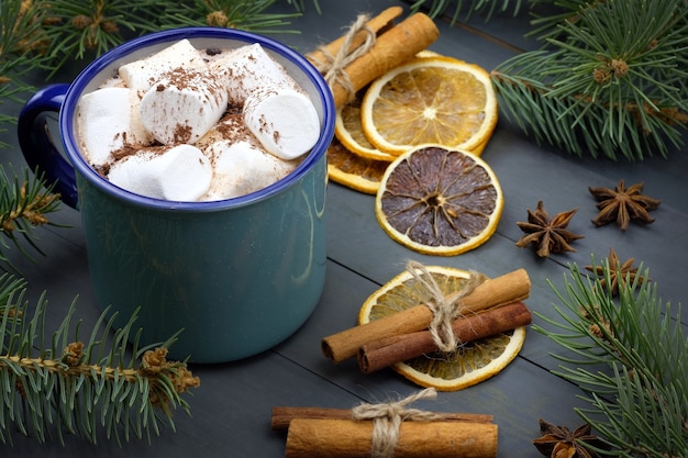 Caneca de cacau com marshmallows e um pau de canela e laranjas secas