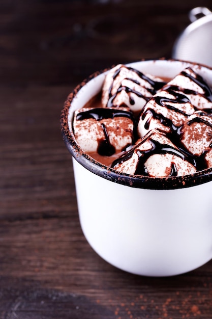 Caneca de cacau com marshmallows em fundo de madeira