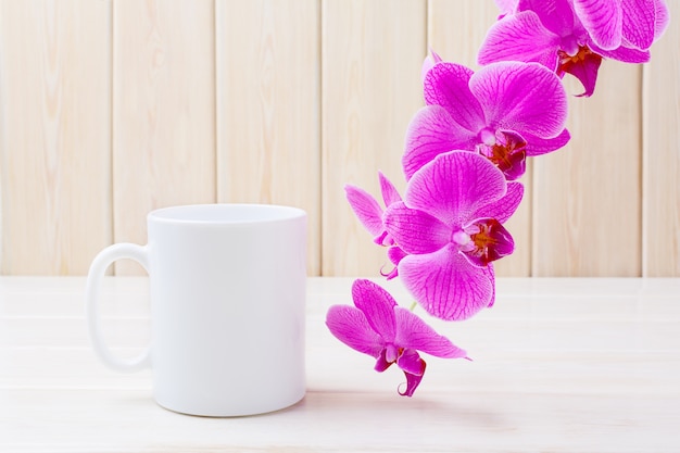 Caneca de café branco com orquídea rosa