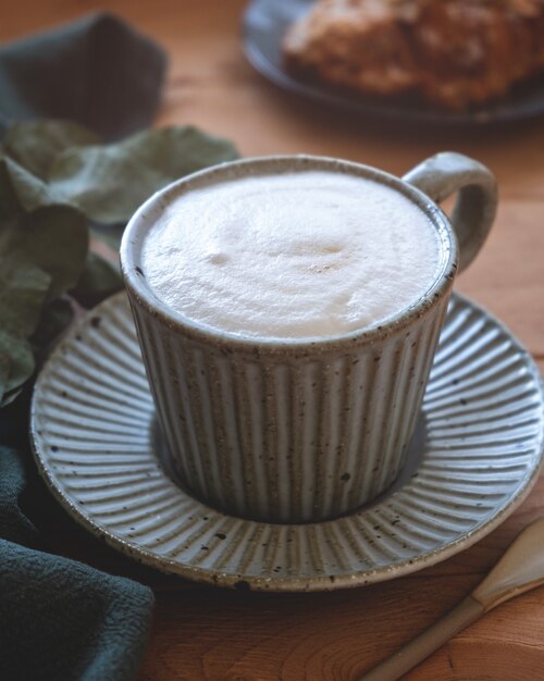 Caneca de café cappuccino em pires e croissant.