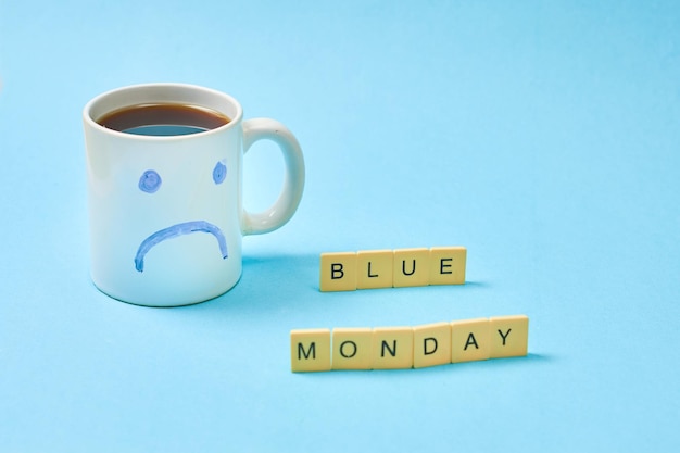 Foto caneca de café com cara triste desenhada conceito de data de segunda-feira azul