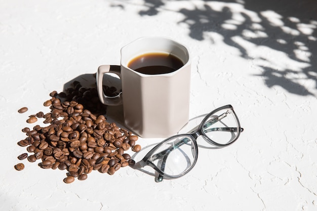 Caneca de café, copos e um monte de grãos de café