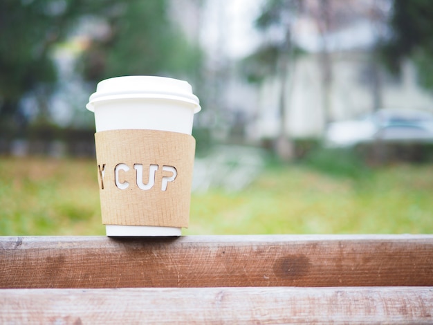 Caneca de café descartável de manhã no parque no banco