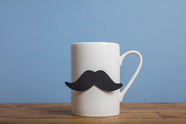 Caneca de café do dia dos pais com bigode de papel contra um fundo azul