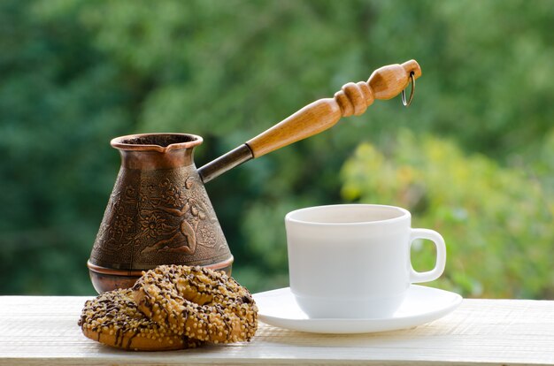 Caneca de café, dois biscoitos e Cezve de cobre na mesa dos cafés de rua