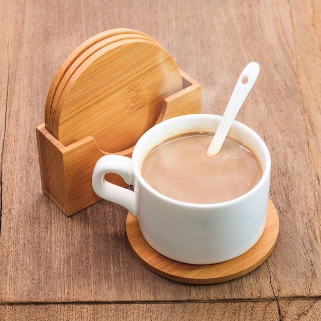 Caneca de café e porta copos da bebida no fundo de madeira.