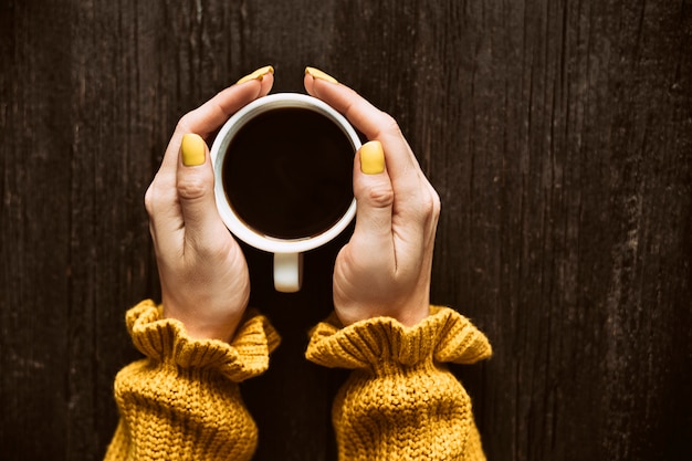 Foto caneca de café em uma mão feminina.