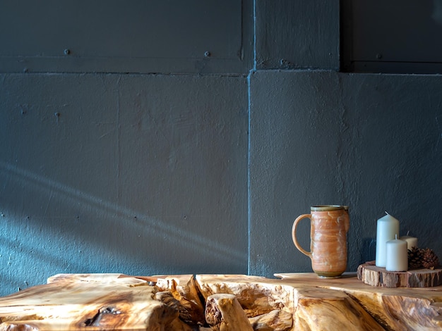 Caneca de cerâmica com decoração de velas de cera branca na mesa de madeira no fundo da parede de concreto pintada de azul