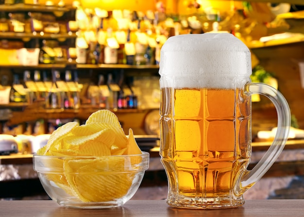 Caneca de cerveja e batatas fritas na mesa no bar