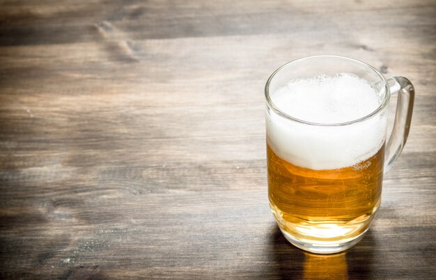 Caneca de cerveja fresca. Em uma mesa de madeira.