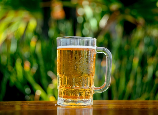 Caneca de cerveja gelada com espuma em cima da mesa.