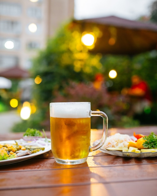 Caneca de cerveja na mesa servida no café com terraço