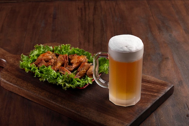 Foto caneca de cerveja na tábua de madeira com porção de frango frito