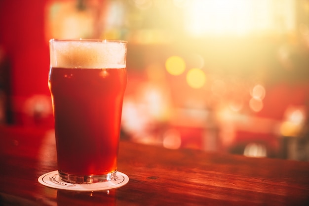 Caneca de cerveja vermelha completa no bar