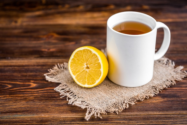 Caneca de chá quente com limão na superfície de madeira. Doença catarral. Temporada de gripe.