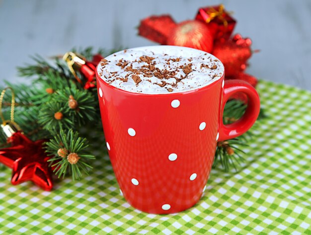 Caneca de chocolate quente com creme na cor, no guardanapo, no fundo das decorações de Natal